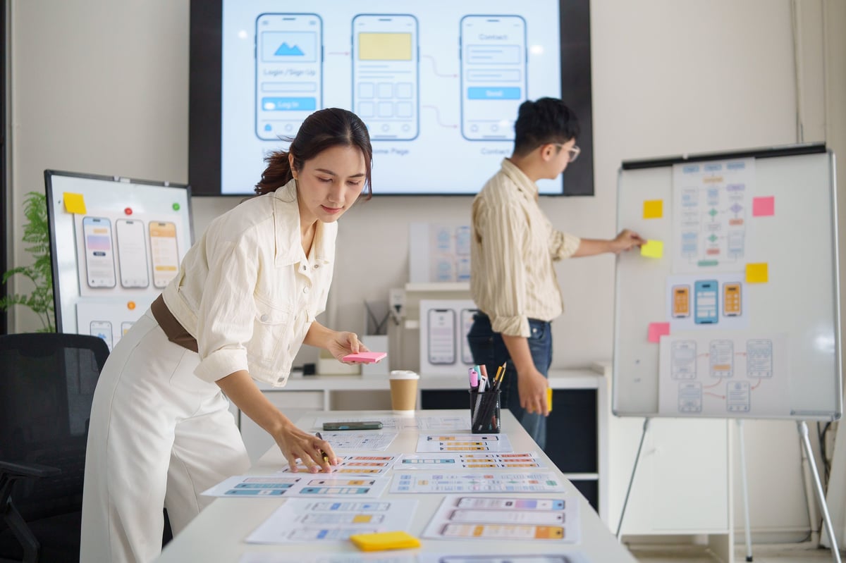 Designer sketching a mobile interface layout with sticky notes